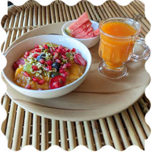 A bowl of fruit and a glass of juice in the plate at India Yoga School.