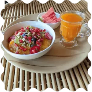Food dish at India Yoga School A bowl of fruit and a glass of juice in the plate at India Yoga School.